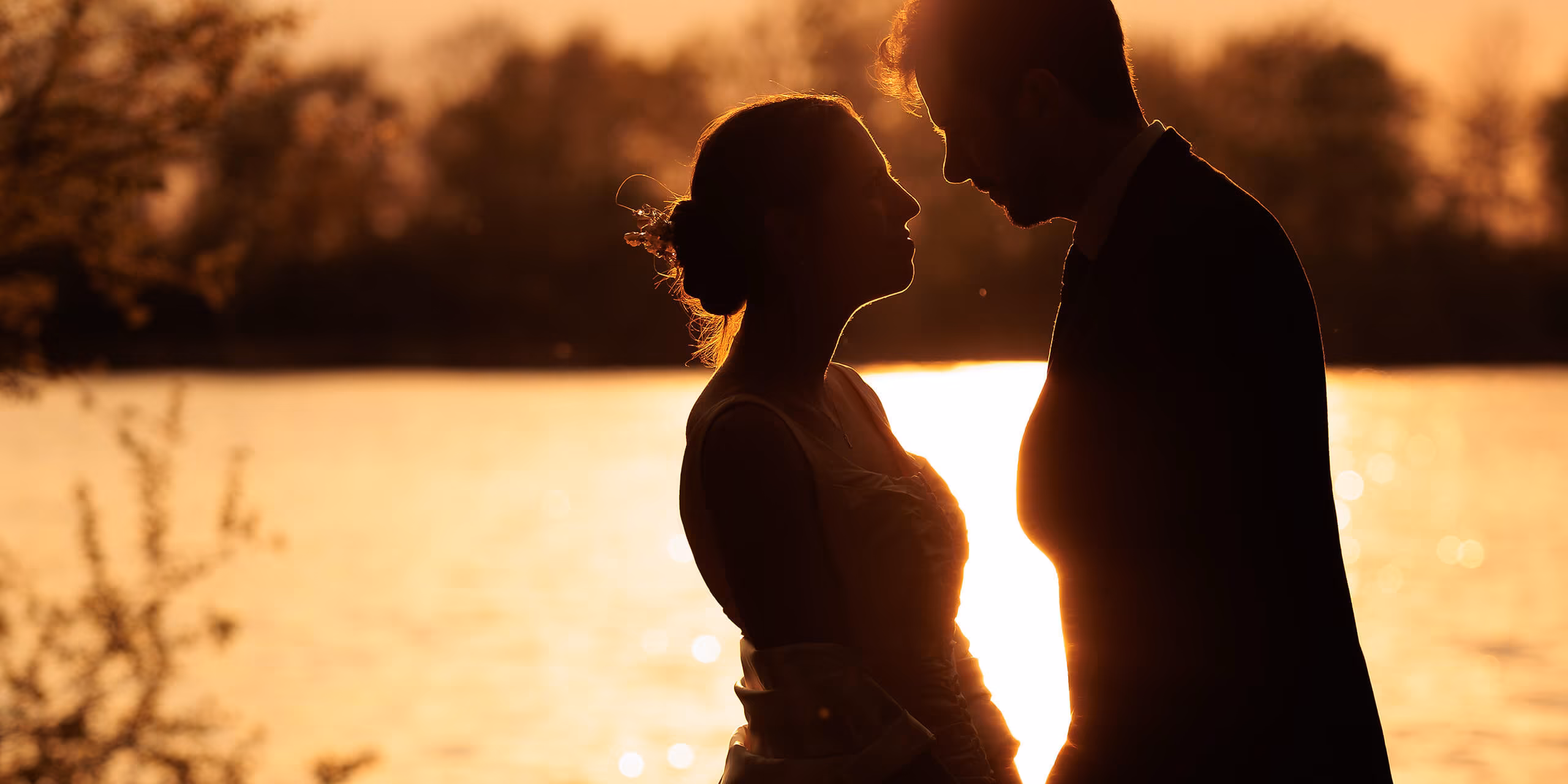 Silhouette romantique de couple de mariés au bord de l'eau au coucher du soleil en Moselle - Photographe mariage Grand Est
