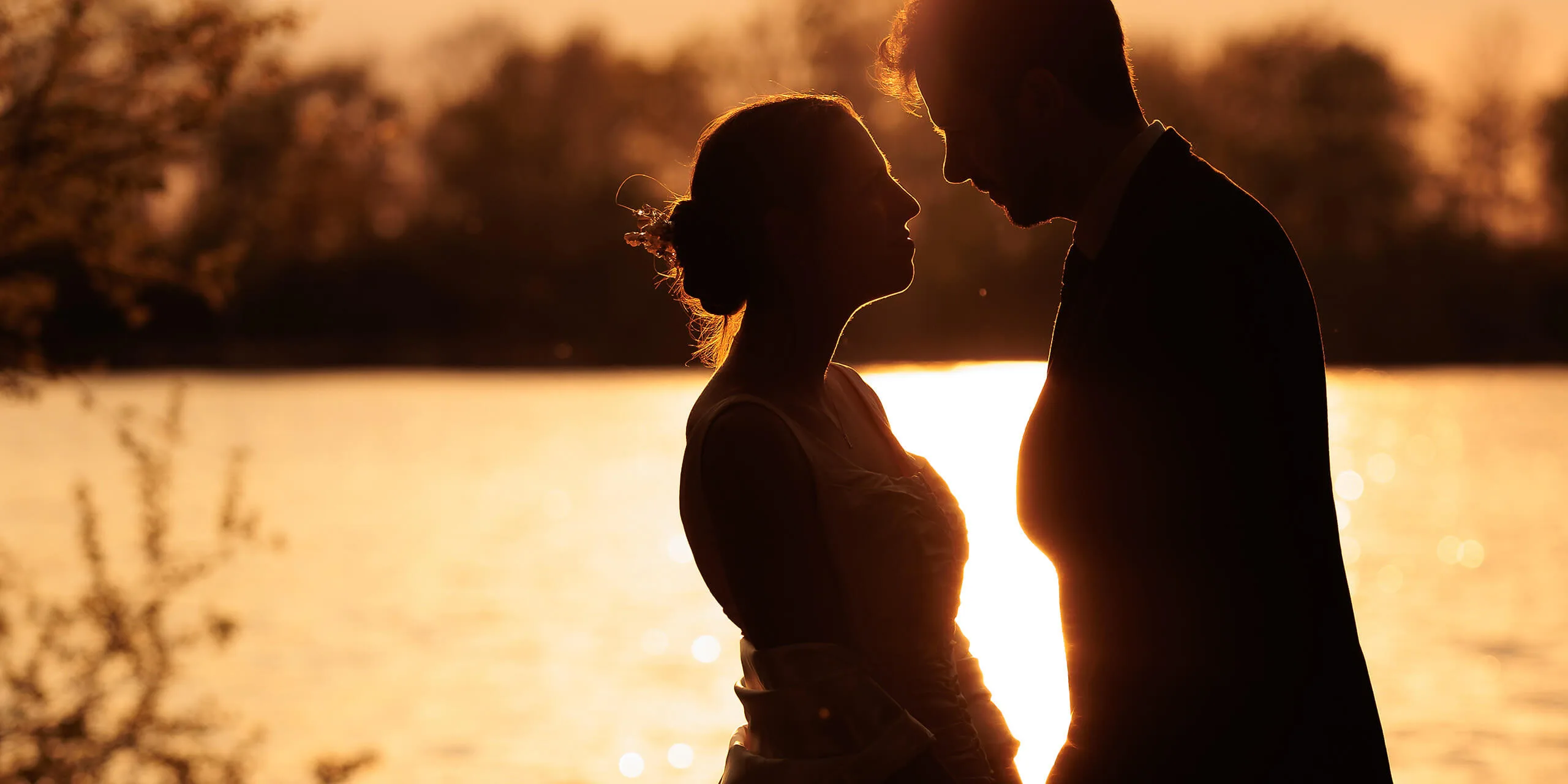 Silhouette romantique de couple de mariés au bord de l'eau au coucher du soleil en Moselle - Photographe mariage Grand Est