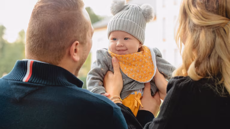 Parents avec leur bébé souriant lors d'une séance photo famille au parc de l'Orangerie à Strasbourg - Photographe naissance Alsace