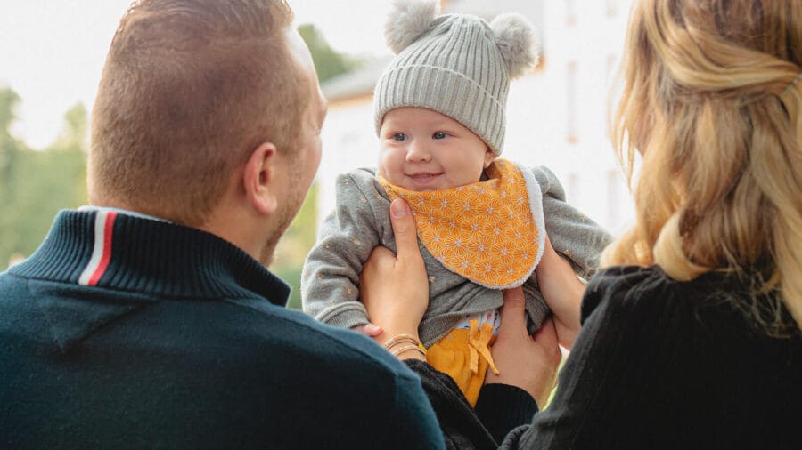 Parents avec leur bébé souriant lors d'une séance photo famille au parc de l'Orangerie à Strasbourg - Photographe naissance Alsace