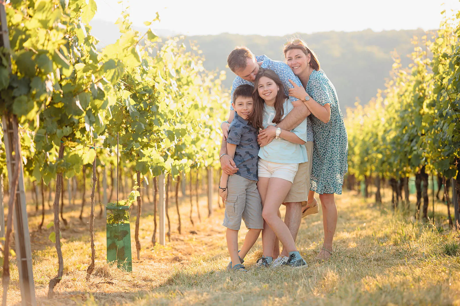 Famille souriante lors d'une séance photo dans un vignoble d'Alsace au coucher du soleil - Photographe famille Obernai