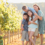 Famille souriante lors d'une séance photo dans un vignoble d'Alsace au coucher du soleil - Photographe famille Obernai
