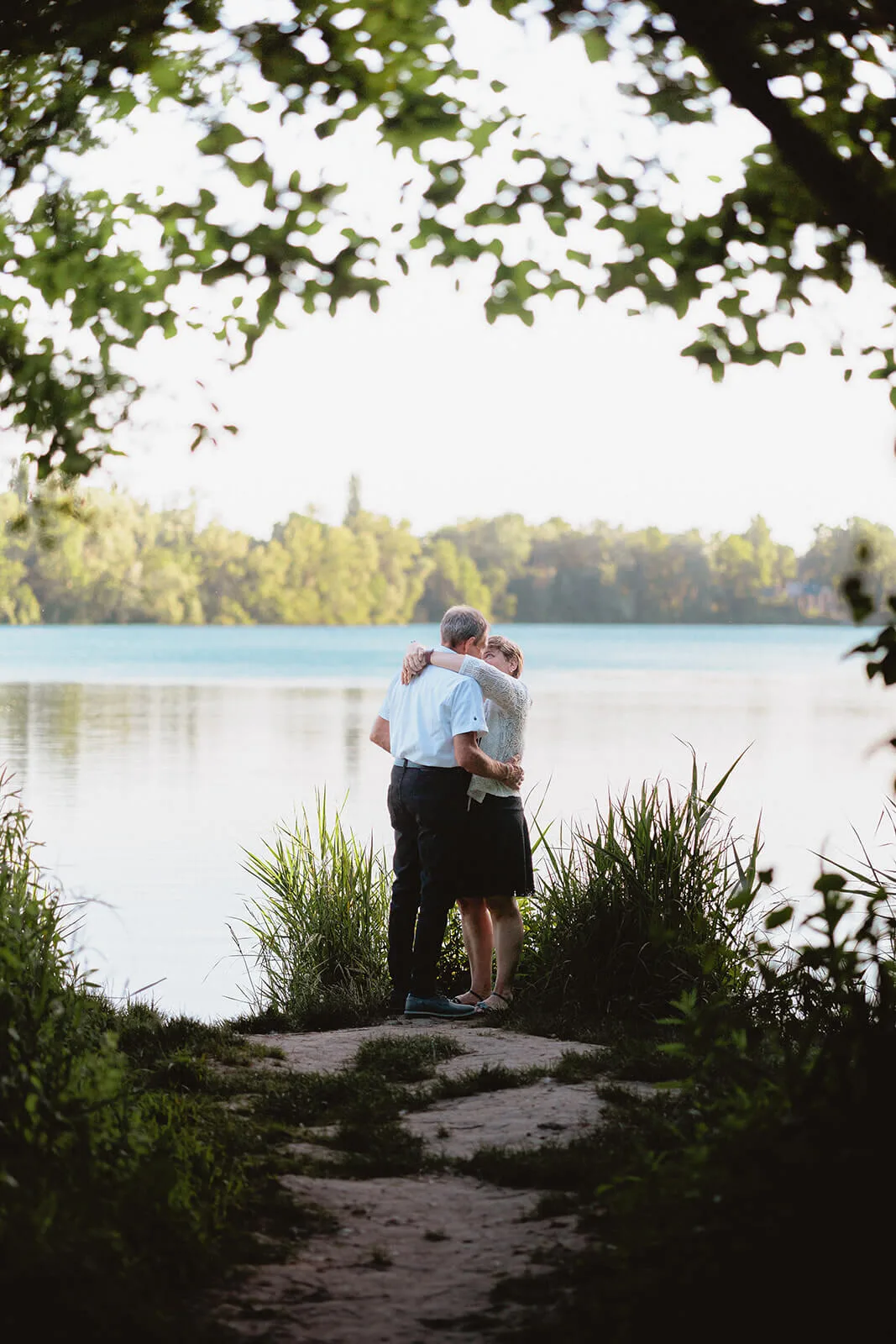 Couple enlacé au bord d'un lac lors d'une séance engagement en Alsace