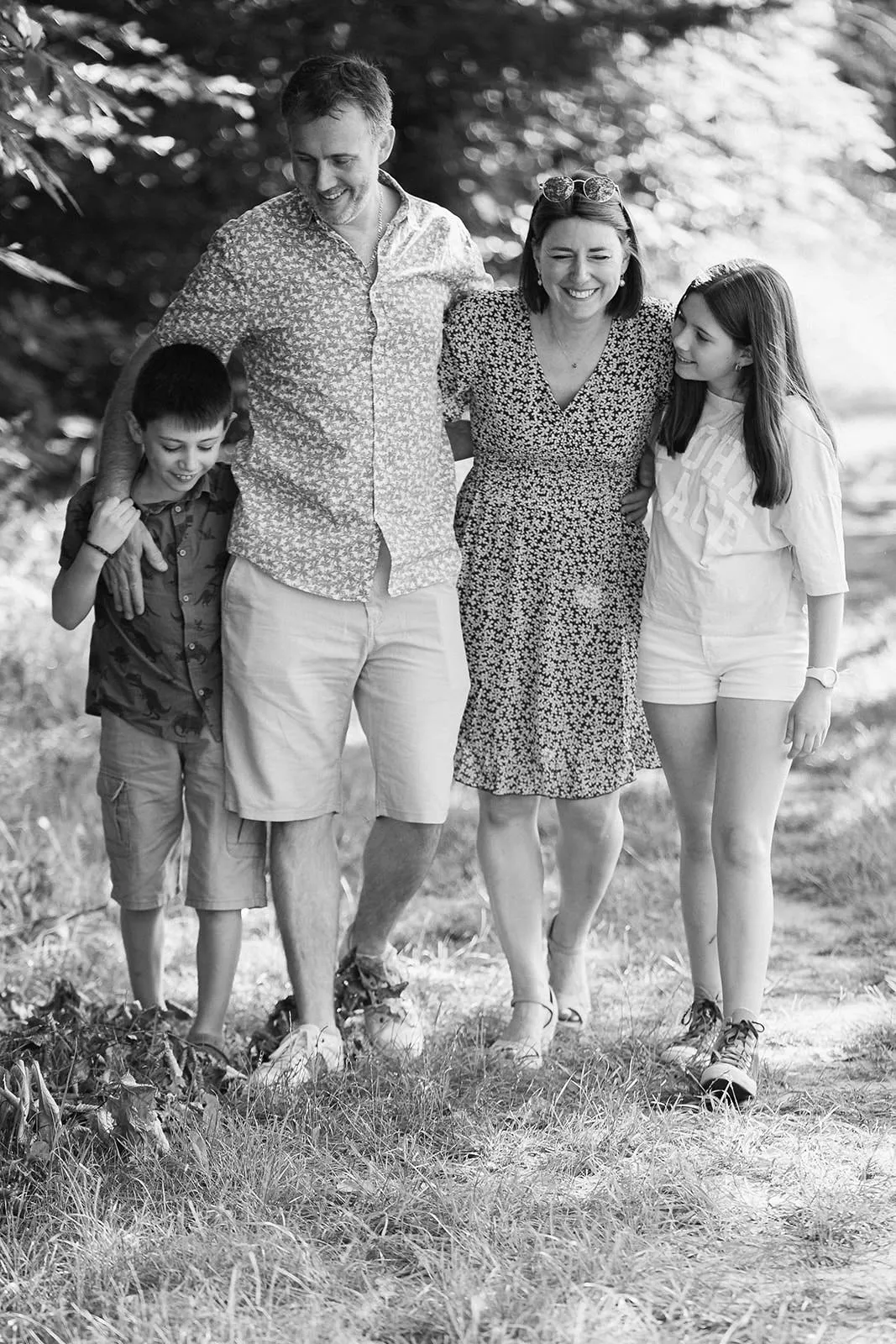 Famille marchant bras dessus bras dessous sur un chemin forestier, portrait noir et blanc