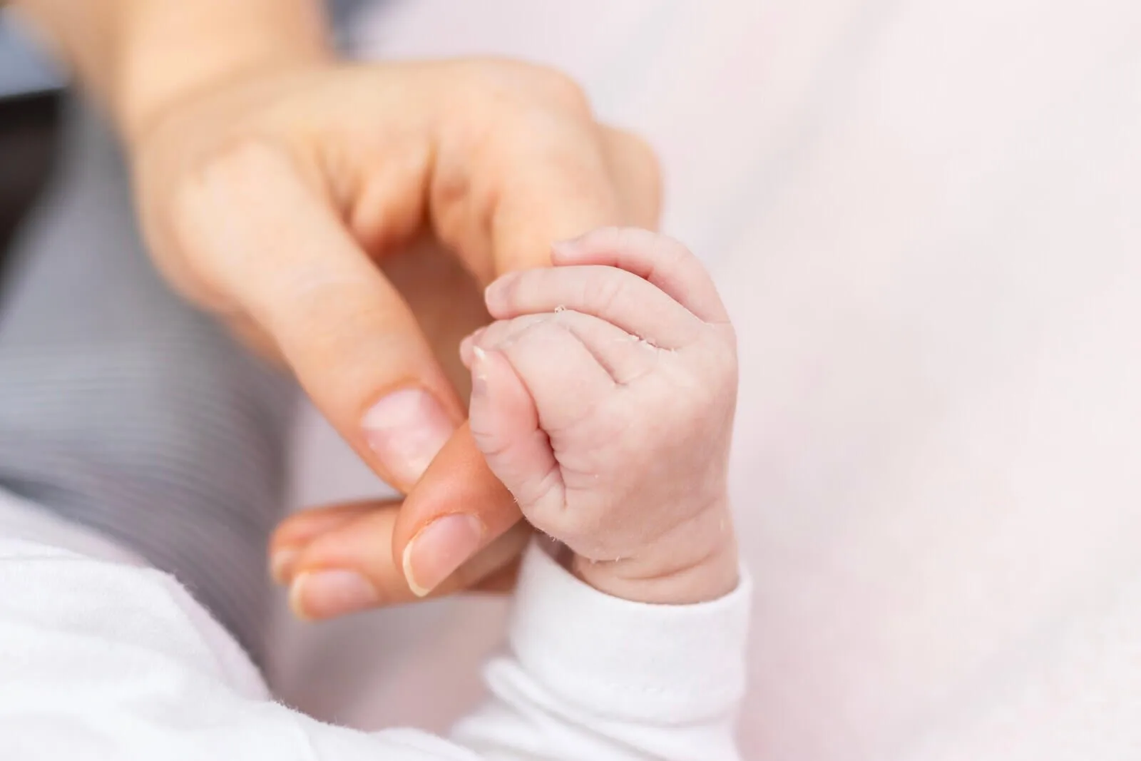 Gros plan sur la main d'un nouveau-né serrant le doigt de sa maman lors d'une séance nouveau-né