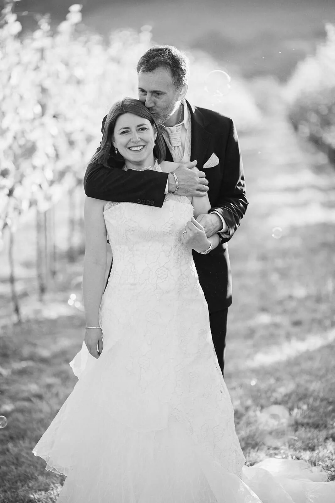 Marié embrassant le front de la mariée au milieu des vignes, photo noir et blanc