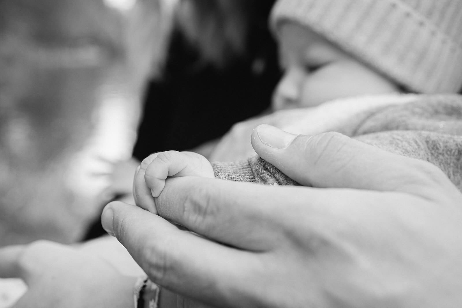 Petite main de bébé serrant celle de son parent au parc de l'Orangerie
