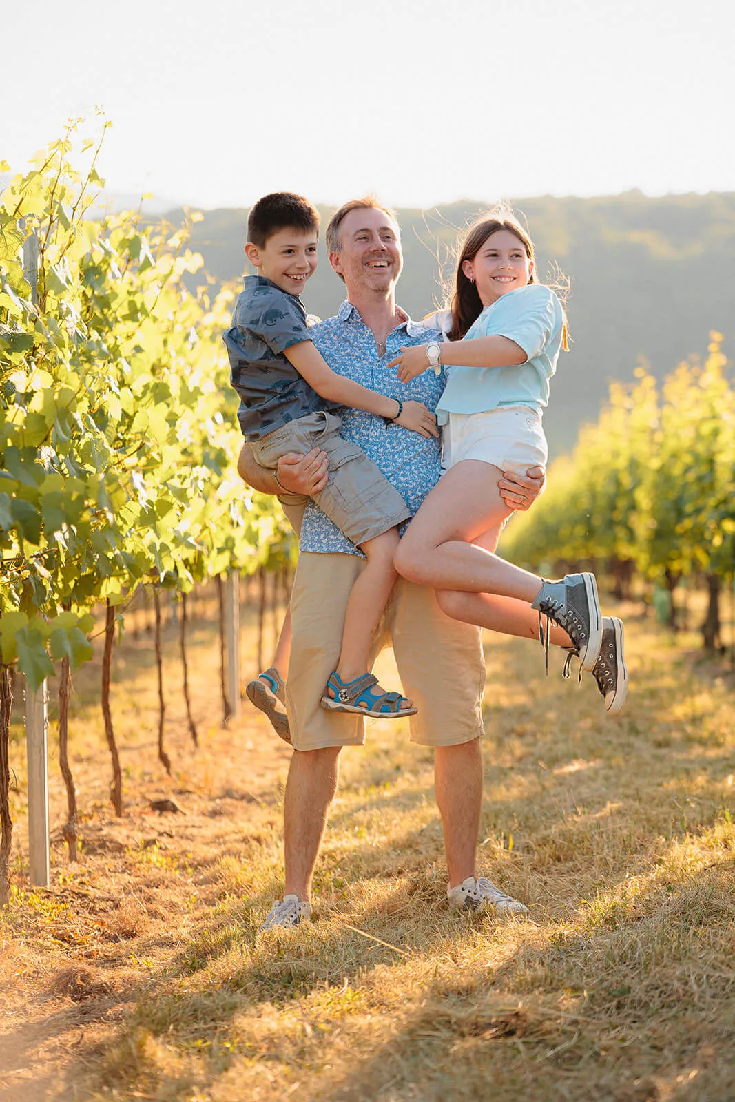 Père portant ses enfants dans les vignes près de Rosheim à l'heure dorée